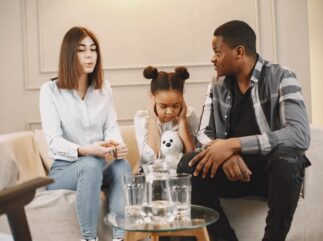 Two parents discussing custody issues with a distraught child on the couch
