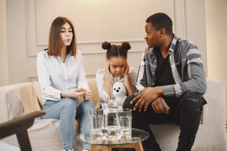 Two parents discussing custody issues with a distraught child on the couch