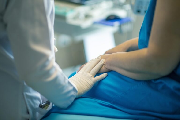 Healthcare professional gently holding a patient's hand during an examination
