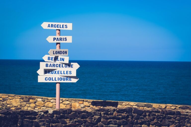 Directional signs pointing different ways beside the ocean