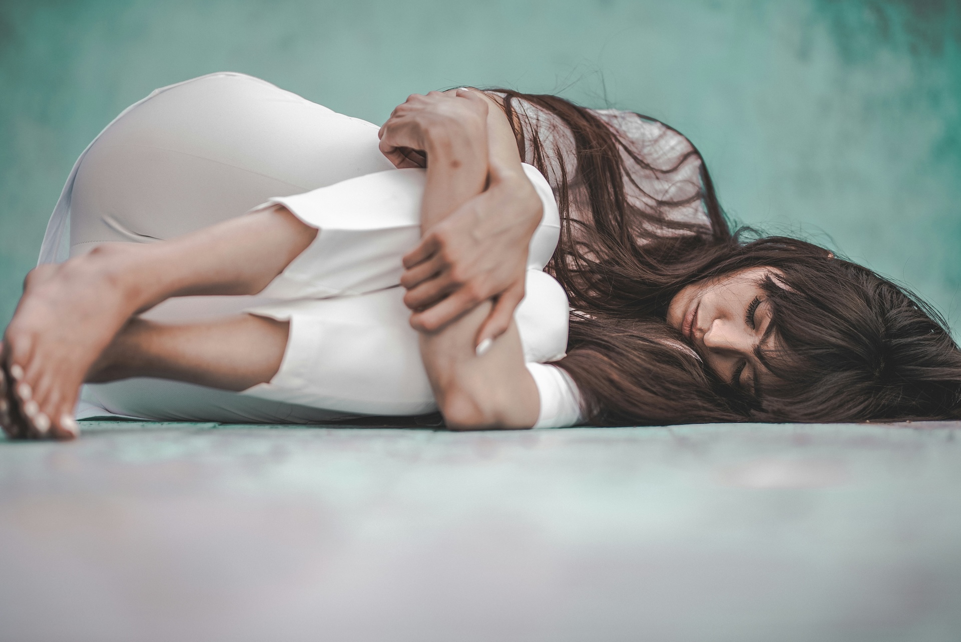 Woman lying curled on her side with her arms around her knees