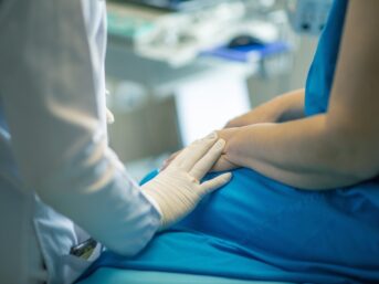 Healthcare professional gently holding a patient's hand during an examination