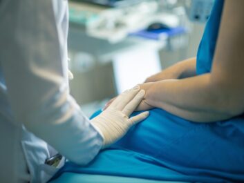 Healthcare professional gently holding a patient's hand during an examination