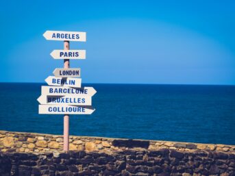 Directional signs pointing different ways beside the ocean