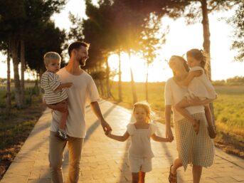 Family walking together along a tree-lined road